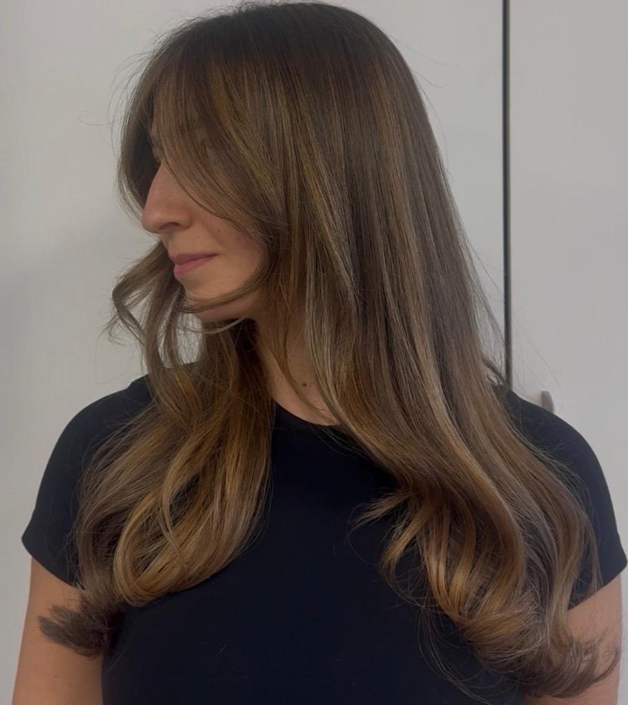 Warm brown waves with honey highlights and curtain bangs