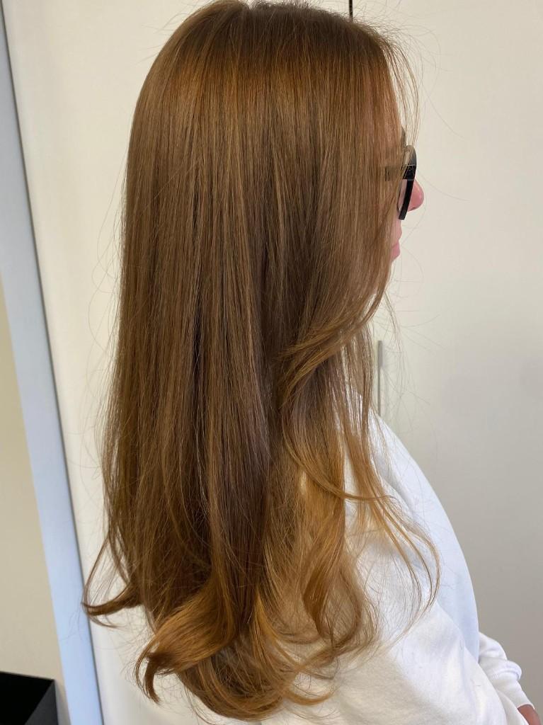 Long honey balayage with soft curled ends, side profile
